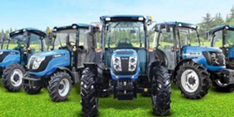 Blue Solis tractors lined up in a field under clear skies, showcasing compact utility models.