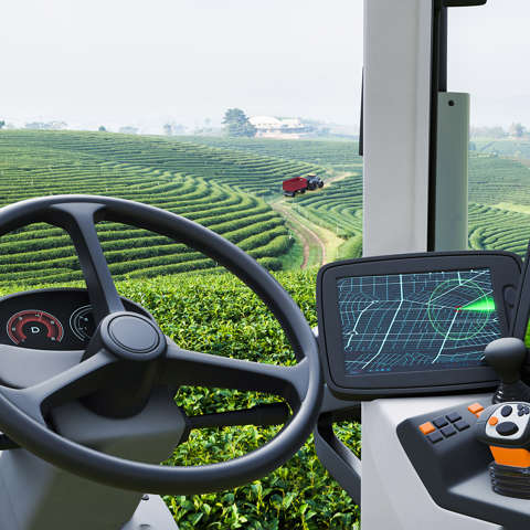 A GPS navigation screen in the cab of a tractor positioned in lush green fields.