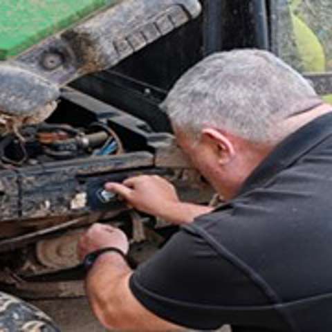 Martyn Leigh in a black VIN CHIP branded polo shirt installing VIN CHIP on a John Deere Gator.