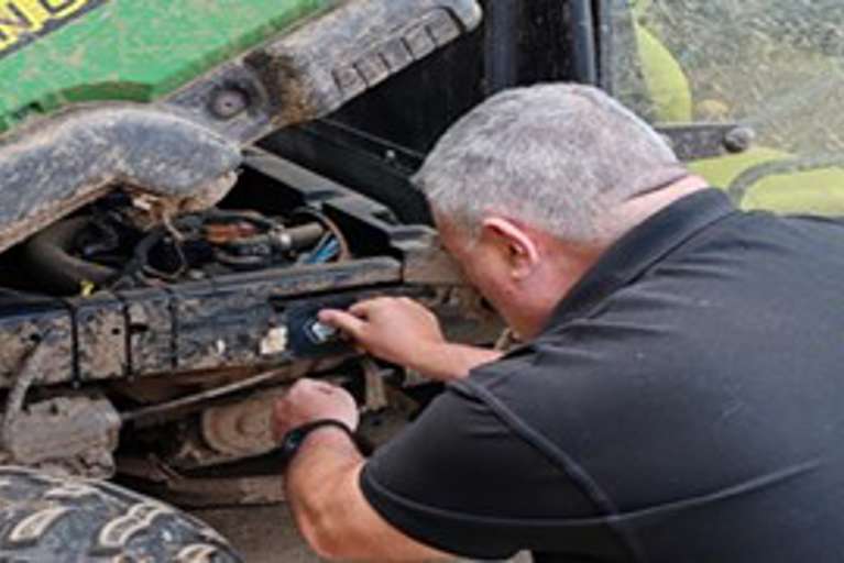 Martyn Leigh in a black VIN CHIP branded polo shirt installing VIN CHIP on a John Deere Gator.