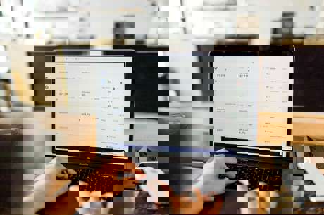 A dealership staff member focused on laptop tasks in a back office setting.