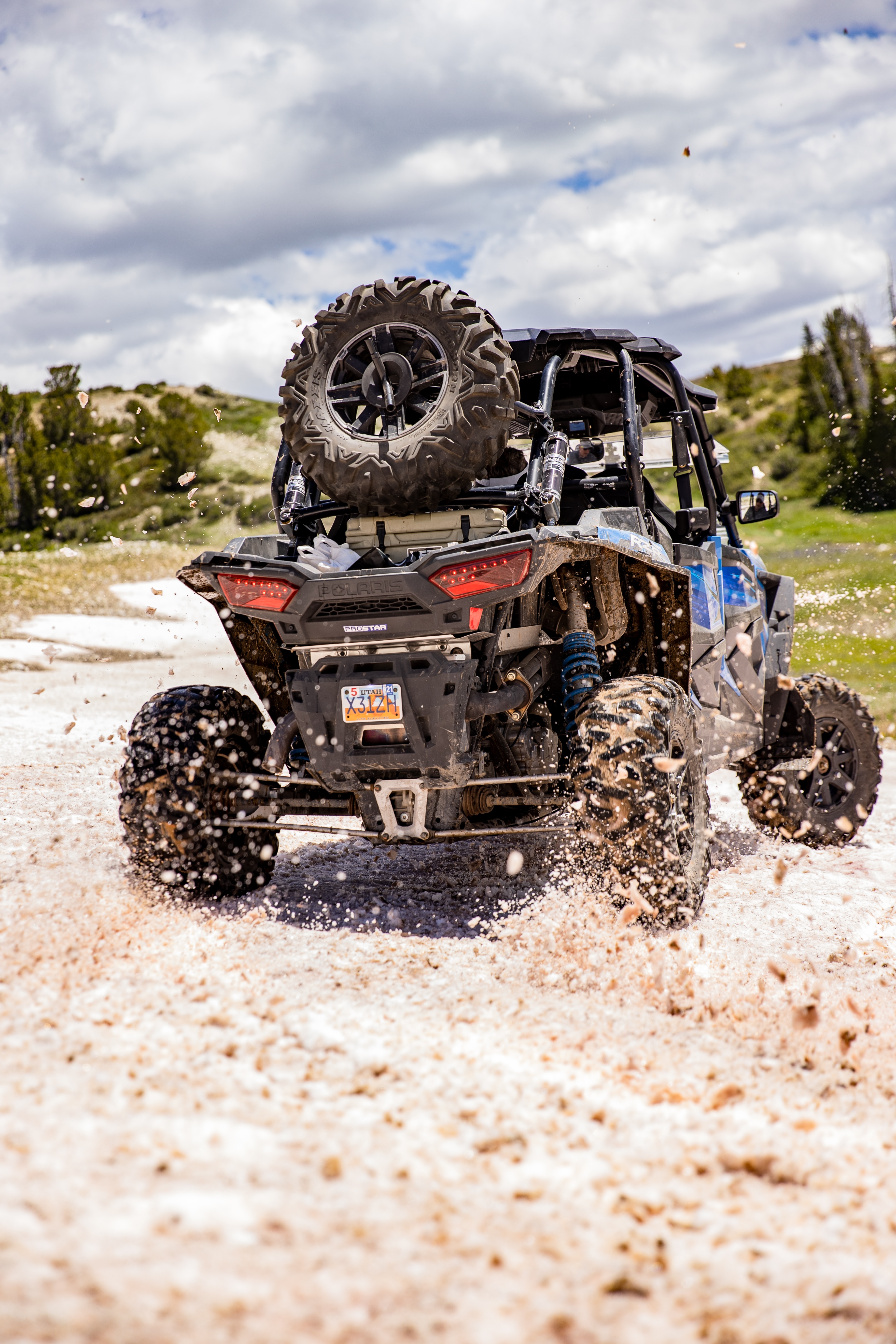 Blue UTV in motion, creating a spray of sand on a dune buggy adventure.