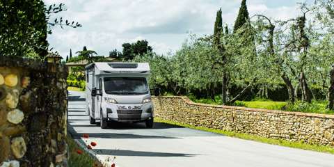 White motorhome driving through picturesque countryside scenery.