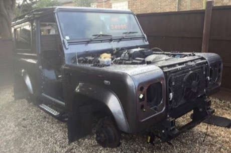Damaged black Land Rover lacking wheels and significant bodywork components.