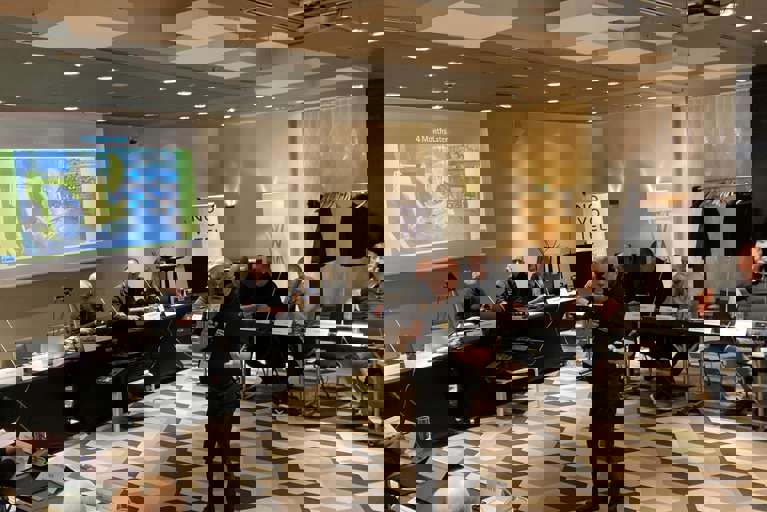 Nick Mayell leading a classroom training session with a PowerPoint presentation displayed on a screen.