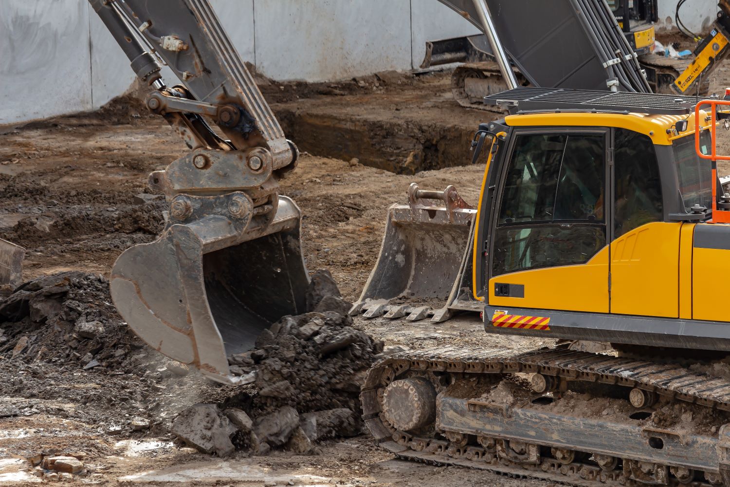 Yellow excavator actively working on a site, moving earth.