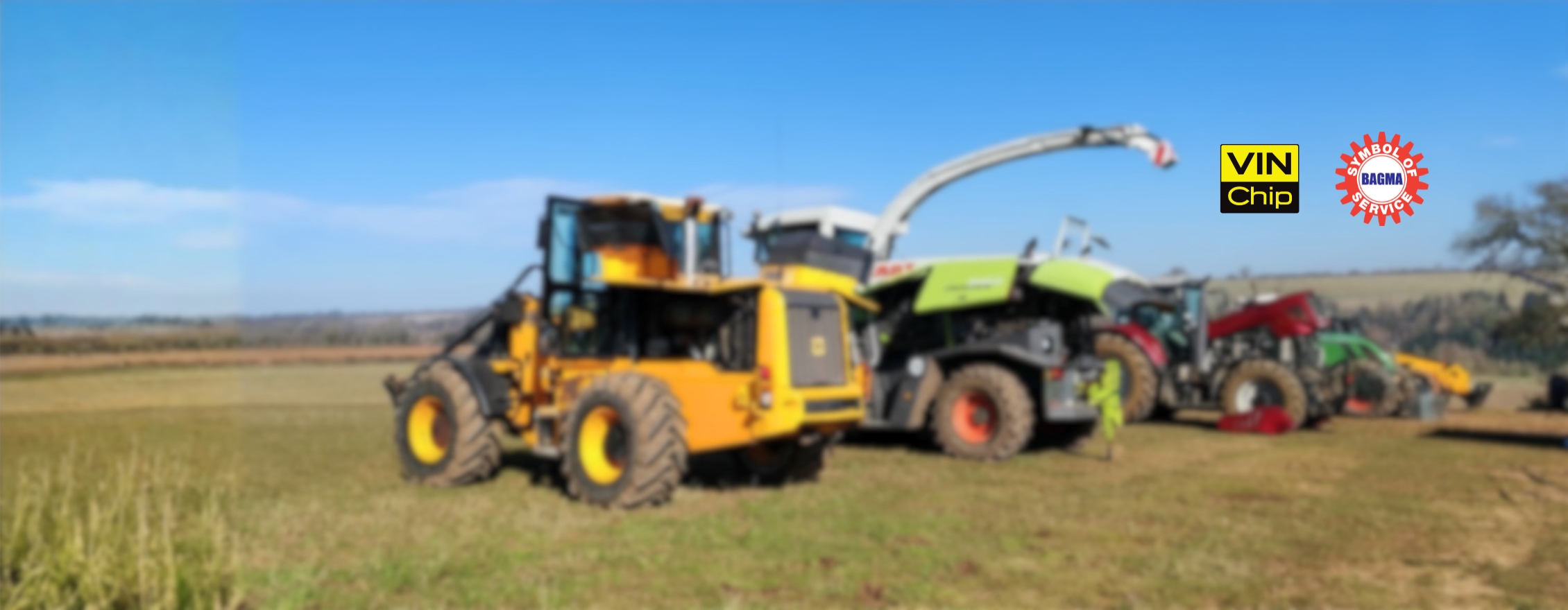 A Line Of Tractors And Agri Machinery On A Green Field W Logos
