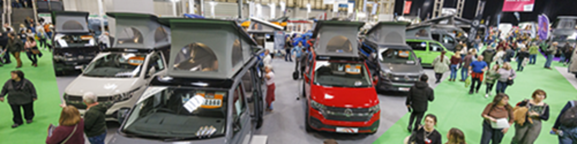 Attendees exploring the Caravan, Camping & Motorhome Show, surrounded by various campervans.