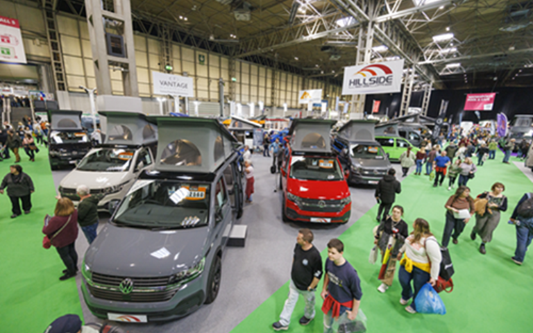 Attendees exploring the Caravan, Camping & Motorhome Show, surrounded by various campervans.