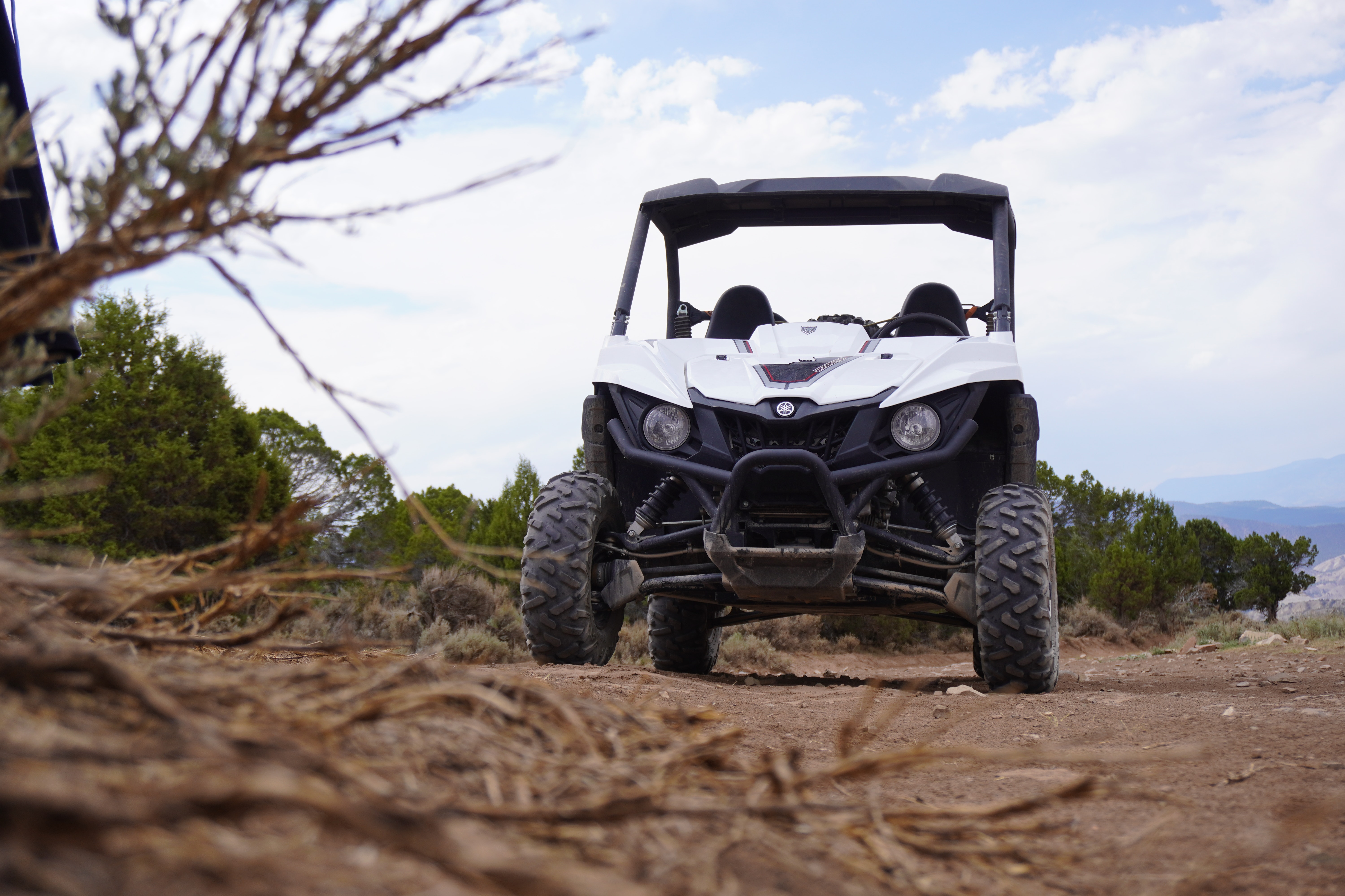A white side-by-side UTV parked on a hilltop, with brown foliage framing the foreground.