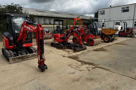 A collection of construction equipment parked side by side in a machinery yard.