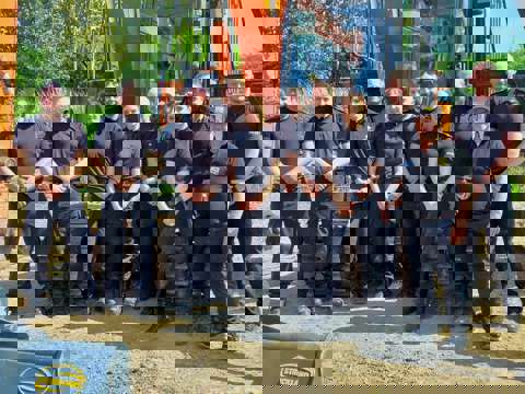 Ten Kent Police officers in blue uniforms with VIN Chip trainer, lined up in front of heavy machinery during IMI theft awareness training.