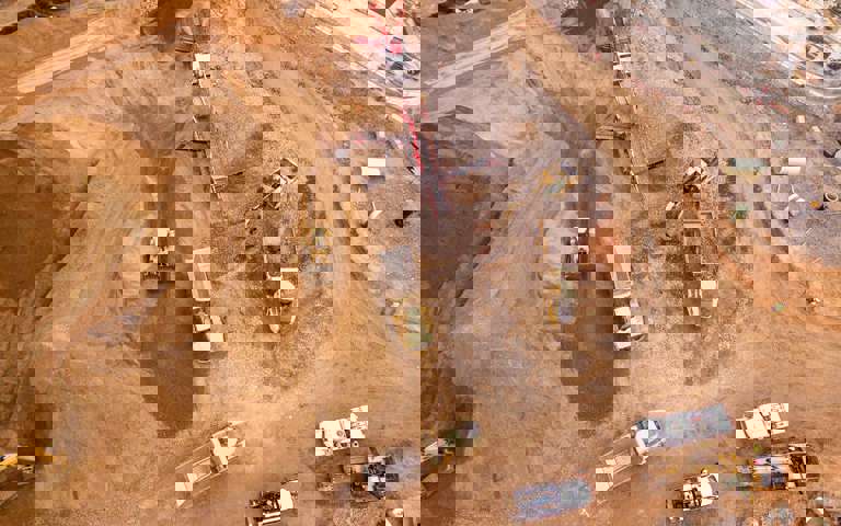 A construction site bustling with activity, featuring trucks filled with earth.