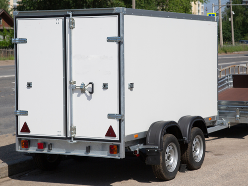 White enclosed trailer parked on the roadside.